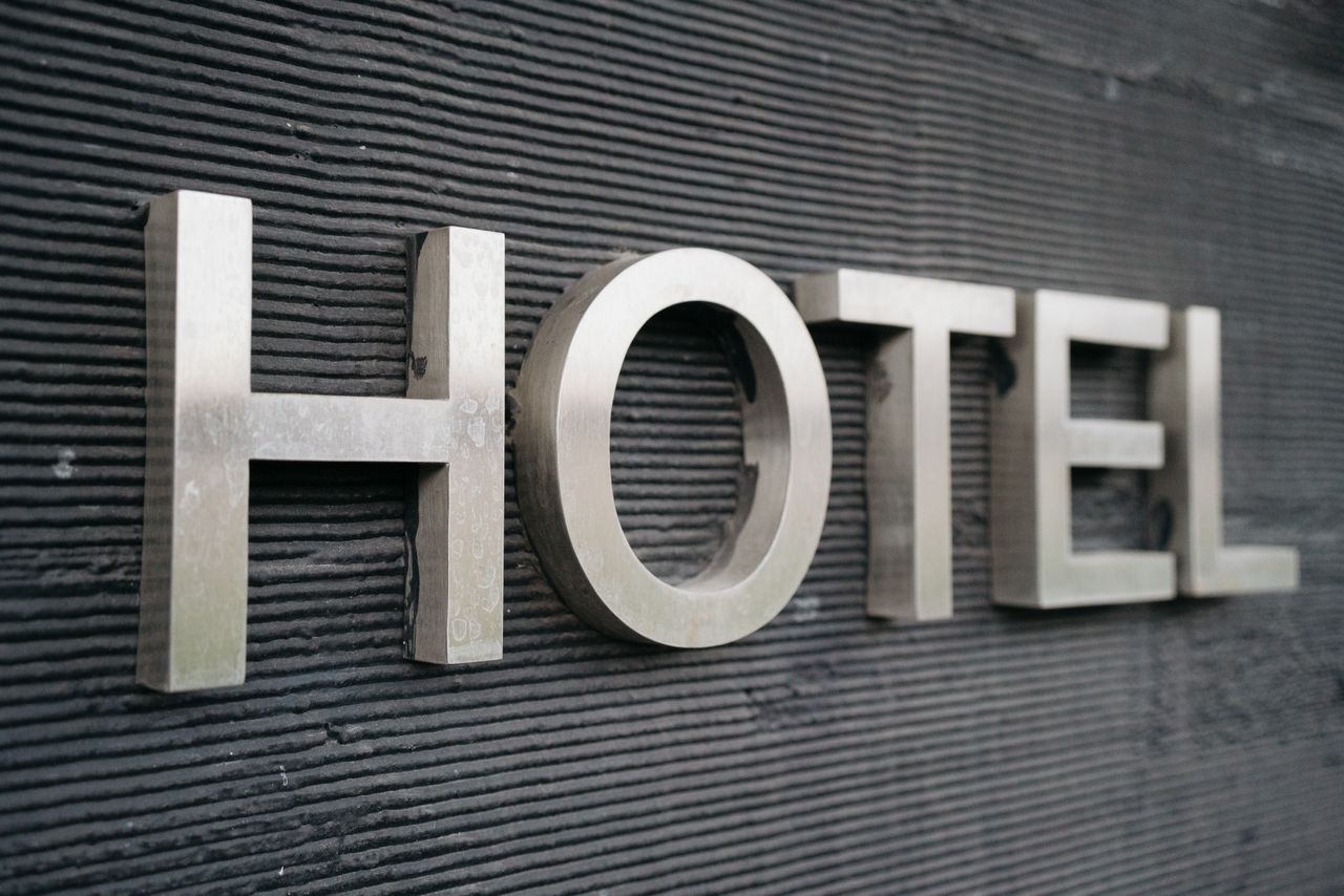 Close-up of a metallic hotel sign mounted on a textured wall.